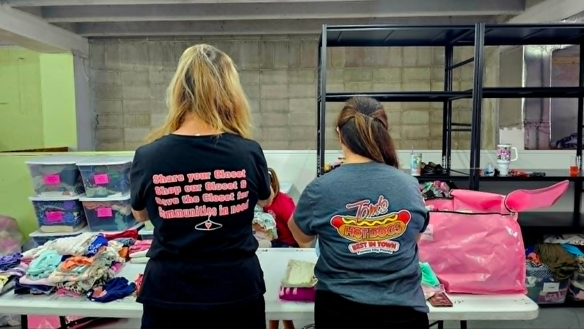 Two women sorting donated clothing items