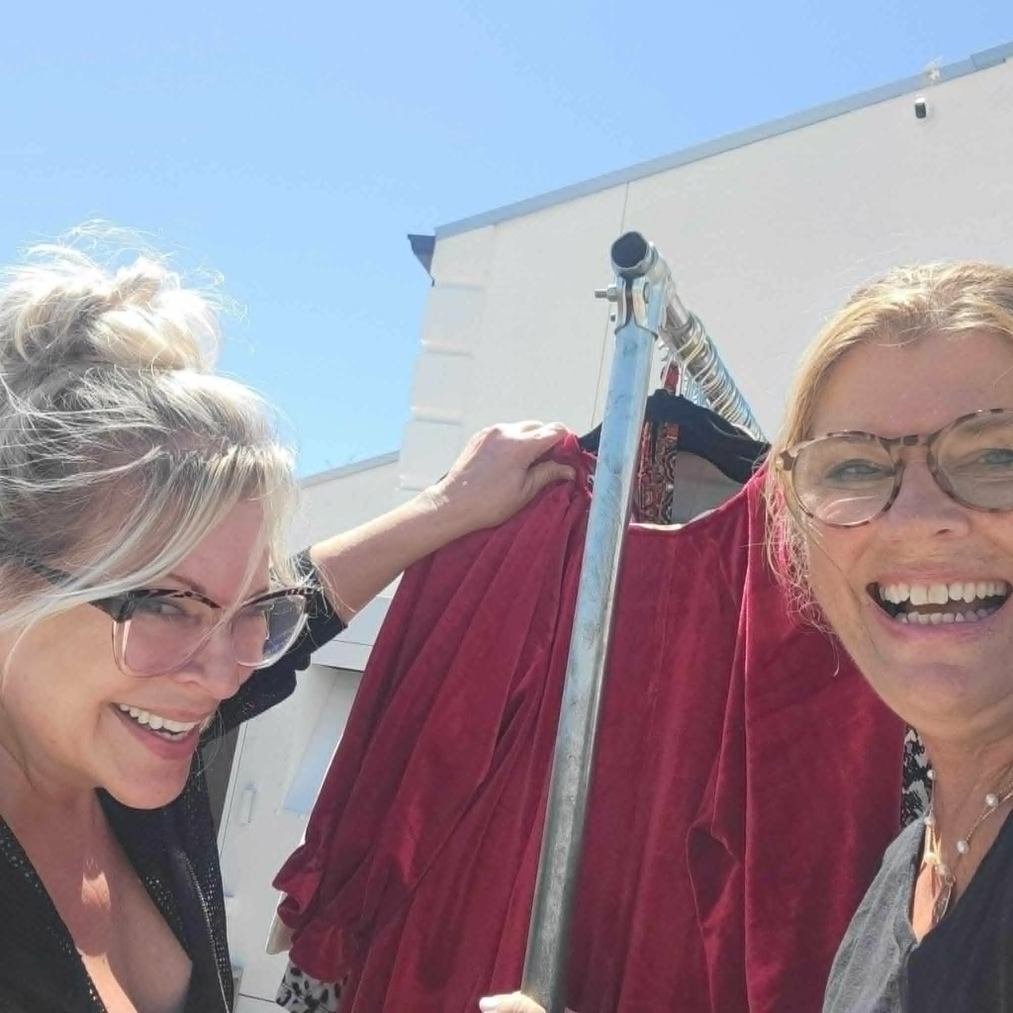 Two women hanging red clothes on rooftop